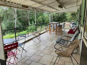 eine abgeschirmte Veranda mit Stühlen, Tischen und einem Tisch in der Unterkunft Maison avec 2 appartements, jacuzzi et accès privé à la rivière in Ladern-sur-Lauquet