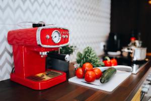 un mixer rosso appoggiato su un bancone con pomodori e cetrioli di Zur Burg a Bad Bentheim