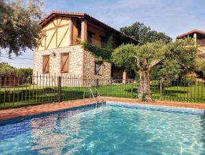 a swimming pool in front of a house at Hotel Rural La Covacha in Losar de la Vera