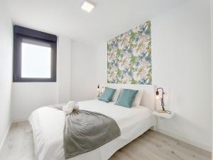 a white bedroom with a large white bed with blue pillows at El Retiro in Las Palmas de Gran Canaria