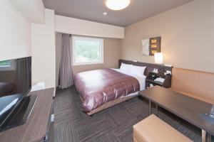 Hotel Route-Inn Saiki Ekimae tesisinde bir odada yatak veya yataklar