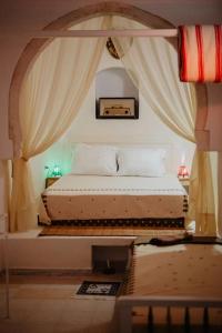 a bed in a room with curtains and a table at Houch ZanZouri in Houmt Souk