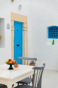 a table with two chairs and a blue door at Houch ZanZouri in Houmt Souk