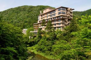 a building on a hill next to a river at Yamanaka Onsen Kissho Yamanaka in Kaga