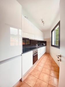 a kitchen with white cabinets and a window at Village Square Coastal Apartment 3G in Machico