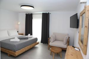 a small bedroom with a bed and a chair at White Dream Suites Antiparos in Antiparos