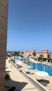 a pool with chairs and umbrellas next to a body of water at Serene Selena Bay Apartments in Hurghada +6 photos