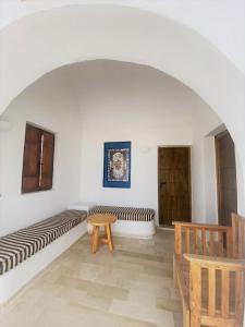 Habitación blanca con banco y mesa en Hôtel Djerba Authentique - Au centre de Midoun en Midoun