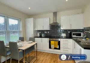 a kitchen with white cabinets and a table with chairs at Stylish 1 bedroom flat with free parking in Woking