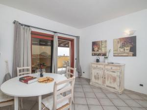 a dining room with a white table and a kitchen at Apartment Timo by Interhome in Casa Tamponi