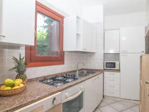 a kitchen with white cabinets and a sink and a window at Apartment Timo by Interhome in Casa Tamponi +23 photos