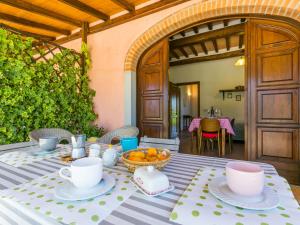 a table with cups and a bowl of fruit on it at Apartment Bianco by Interhome in Suvereto