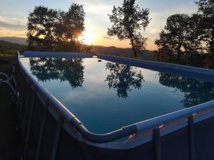 a swimming pool with a sunset in the background at B&B del Fernè in Monte Ombraro