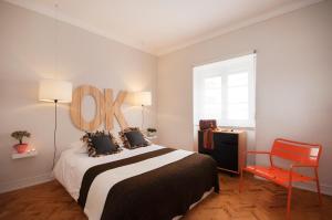 sypialnia z dużym łóżkiem i czerwonym krzesłem w obiekcie Graça - Castle | Lisbon Cheese & Wine Apartments w Lizbonie