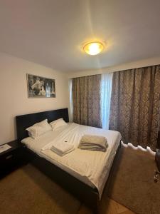 um quarto com uma cama com lençóis brancos e almofadas em Decebal apartment overlooking the boulevard em Bucareste
