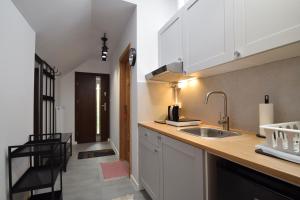 a kitchen with white cabinets and a sink and a hallway at Apartamenty Przy Bałtyckiej in Mrzeżyno