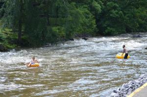 due persone sono in acqua in tubi in un fiume di Creekstone Inn a Pigeon Forge