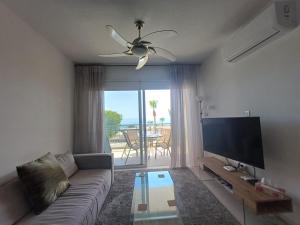 a living room with a couch and a flat screen tv at Kings Palace - Elegant 2 bed sea facing apartment in Paphos City