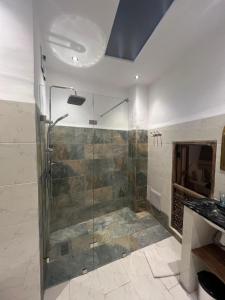 La salle de bains est pourvue d'une douche avec une porte en verre. dans l'établissement Riad Jnan El Cadi, à Marrakech