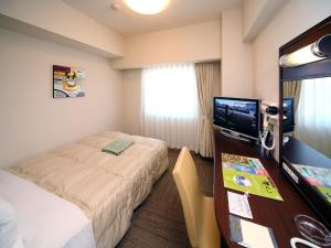 Habitación de hotel con cama y escritorio con TV. en Hotel Route-Inn Utsunomiya Miyukicho -Kokudou4gou- en Utsunomiya