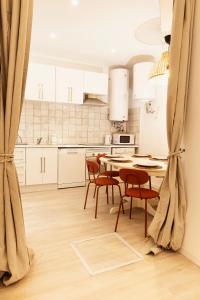 马德里Bravo Murillo Apartment的配有白色橱柜、桌子和椅子的厨房