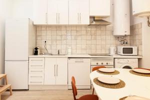 马德里Bravo Murillo Apartment的厨房配有白色橱柜和桌子及椅子 更多40张照片