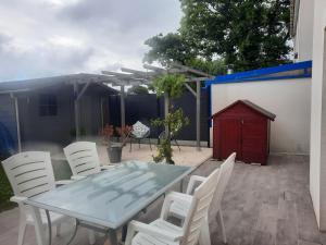 Un patio con una mesa y sillas blancas y ceniza. en Joli pavillon proximité ocean, en Saint-Nazaire