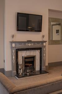 a living room with a fireplace with a television above it at The Enniskillen Hotel and Motel in Enniskillen