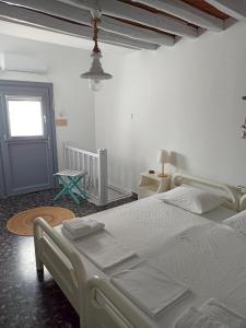 a white bedroom with a large bed and a window at Στου Βάρδα, Χώρα, Σέριφος in Serifos Chora