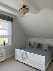 ein weißes Schlafzimmer mit einem Bett und einem Fenster in der Unterkunft Bay Cottage wynajem domków in Swarzewo