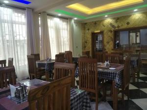 a dining room with tables and chairs and windows at Aves Executive Hotel in Arusha