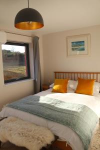 ein Schlafzimmer mit einem Bett mit orangefarbenen Kissen und einem Fenster in der Unterkunft Hector's Row in Tobermory