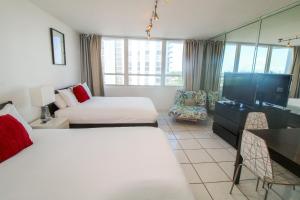 a hotel room with two beds and a flat screen tv at Castle 515 Studio BayView Direct Beach Access, Pool, Tennis, Free Parking in Miami Beach