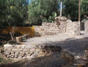 a stone wall in a yard with a fence at La Pirquita in Tilcara
