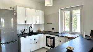 a kitchen with white cabinets and a black counter top at SE104 - Elegante quadrilocale comodo ai servizi in Senigallia
