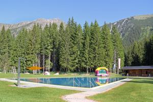 a swimming pool in a field with a house and trees at Haus Daheim in Berwang