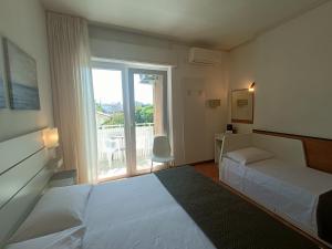 a hotel room with two beds and a balcony at Hotel Merano in Grado