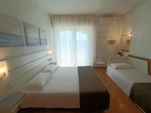a bedroom with two beds and a large window at Hotel Merano in Grado