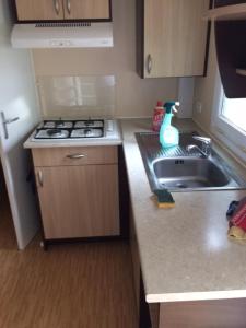 a small kitchen with a sink and a stove at MOBILHOME CHEZ SYLVIE AU CAMPING DE PUJOL in Argelès-sur-Mer +3 photos