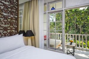 a bedroom with a bed and a balcony with a window at Segara Village Hotel in Sanur