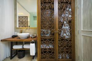 a bathroom with a wooden door with a sink at Segara Village Hotel in Sanur