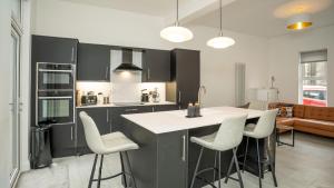 a kitchen with black cabinets and white counter chairs at Luxury Central 4 BDR house by Belfast City Breaks in Belfast
