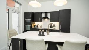 a kitchen with black cabinets and a kitchen island with chairs at Luxury Central 4 BDR house by Belfast City Breaks in Belfast