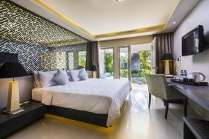 a bedroom with a bed and a desk and a television at Segara Village Hotel in Sanur