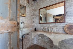 La salle de bains en pierre est pourvue d'un lavabo et d'un miroir. dans l'établissement Torre dei Battagli-Dormi in una torre medievale, à Santarcangelo di Romagna