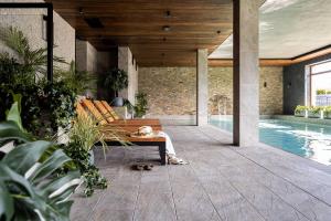 a woman sitting on a couch on a patio with a pool at Tylickie Wzgórze SPA & Wellness - basen, sauna, siłownia, atrakcje dla dzieci in Tylicz