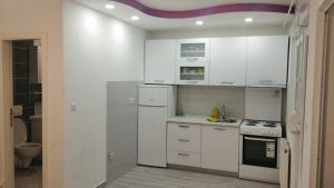 eine Küche mit weißen Schränken und einem Herd mit Backofen in der Unterkunft Apartman Central in Doboj