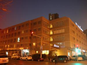 a large building with cars parked in front of it at Jinjiang Inn Beijing Olympics Park in Beijing