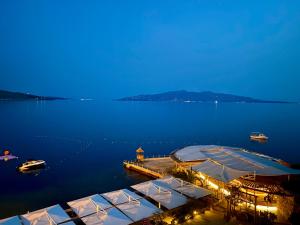 a dock with umbrellas in the water at night at Hotel Nertili in Sarandë