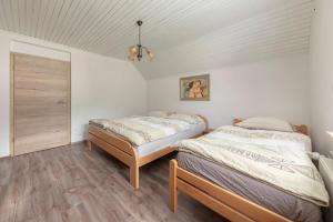 two beds in a room with white walls and wood floors at Apartmaji Seljak in Preddvor